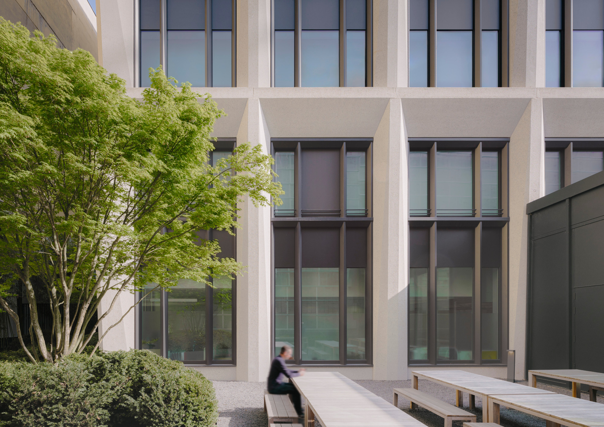 Completed building, outdoor area behind the sawtooth-roof hall, photographed in 2024